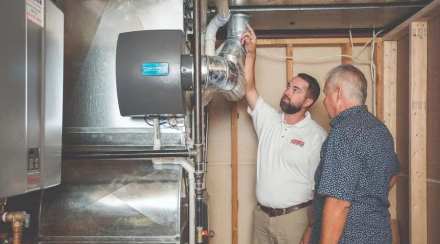 hvac technician shows a homeowner their furnace system